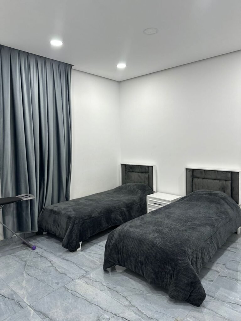 Twin bedroom with velvet bedding and blackout curtains in luxury furnished apartment near Benghazi University