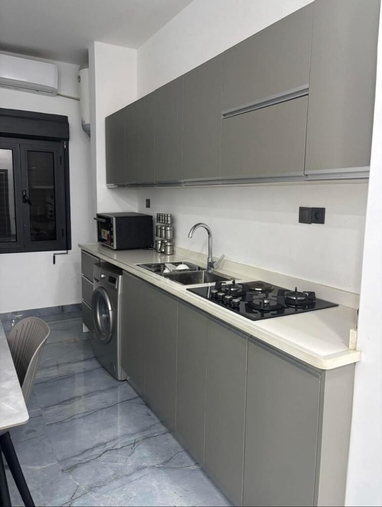 Modern grey kitchen with built-in appliances and full cooking amenities in a luxury apartment near Benghazi University