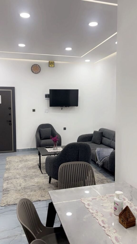 Modern furnished living room with flat-screen TV and grey sofa set in حي الجامعي apartment near Benghazi University